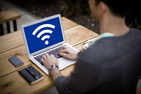 A man is working on his laptop and sees a wifi symbol on the screen.